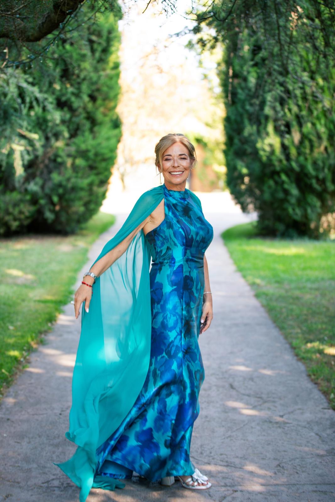 Clienta con el vestido La Dolce Vita en mikado estampado azul y capa de gasa turquesa en un paseo de cipreses